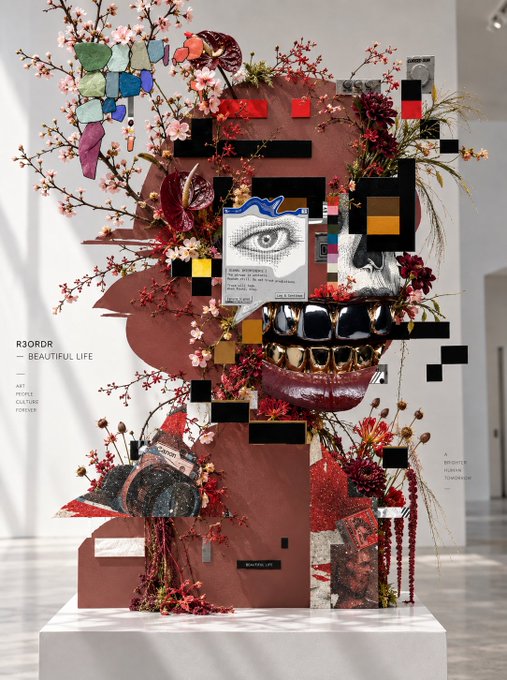 Art installation by RJORDA titled 'Beautiful Life - Art People Culture Forever,' featuring a sculptural face with gold teeth and floral arrangements.