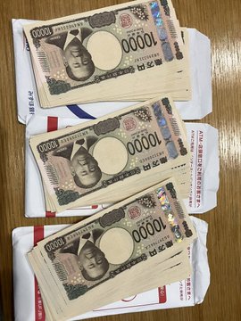 Three bundles of Japanese 10,000 yen notes, each totaling 1,000,000 yen (10,000 yen × 100 bills × 3 stacks = 3 million yen), are stacked on a wooden surface next to shipping envelopes, visually representing the "1 million yen" investment amounts discussed in the post comparing asset performance.