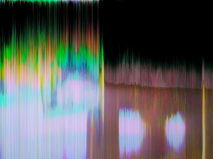 An abstract, colorful image consisting of vertical streaks of green, red, blue, and yellow light against a dark background, with two bright purple/white rectangular light sources at the bottom.