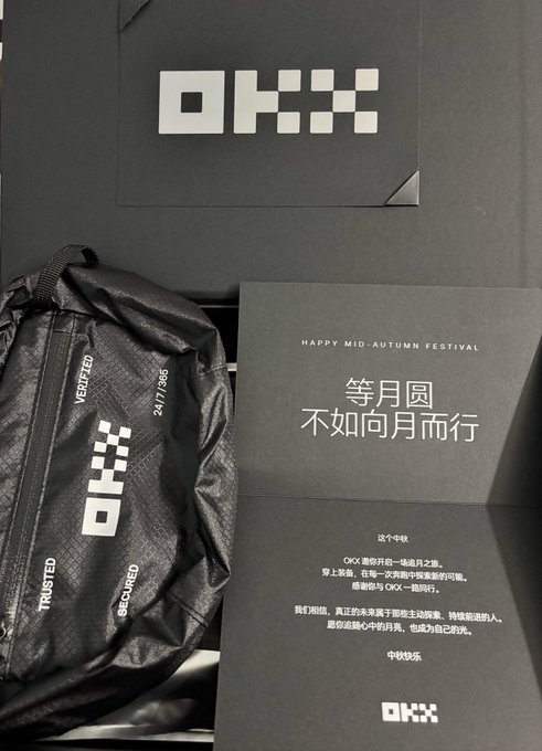 An OKX-branded black bag and Mid-Autumn Festival card with Chinese text including 'HAPPY MID-AUTUMN FESTIVAL' and '等月圆不如向月而行' are displayed in a promotional box.