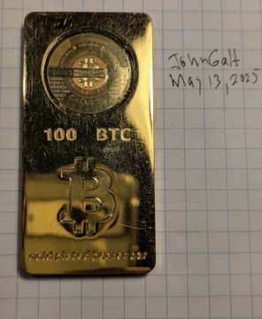 A gold-colored Casascius Bitcoin bar engraved with "100 BTC" sits on grid paper, with a handwritten note reading "John Galt May 13, 2015." The image illustrates the story of an early investor who purchased 100 BTC for $500, only to watch it grow into a million-dollar asset that he struggled to sell even at the $10K milestone.