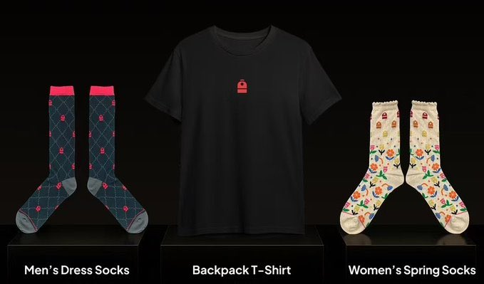 A product display featuring three items on black pedestals: Men's Dress Socks (navy with pink accents), a Backpack T-Shirt (black with small red logo), and Women's Spring Socks (cream with floral pattern).