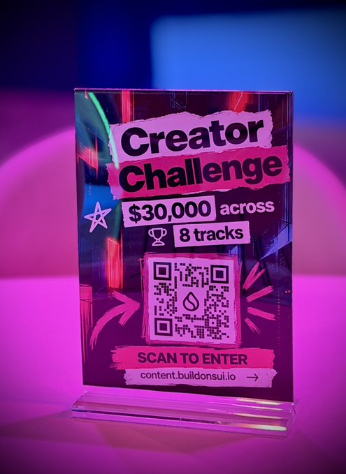 An acrylic sign with neon pink and blue lighting advertising a 'Creator Challenge' offering '$30,000 across 8 tracks' with a QR code to 'SCAN TO ENTER' at content.buildonsui.io.
