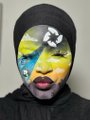 A portrait of a person wearing a black hoodie, with their face covered by colorful paint in yellow, blue, and black patterns.