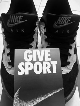 A pair of black Nike Air sneakers is displayed behind a "GIVE SPORT" card, illustrating the challenge's concept of connecting real-world branded products like Nike with their tokenized asset equivalents. The image visually reinforces the post's invitation to identify and match real-world brands to their corresponding rTokens.
