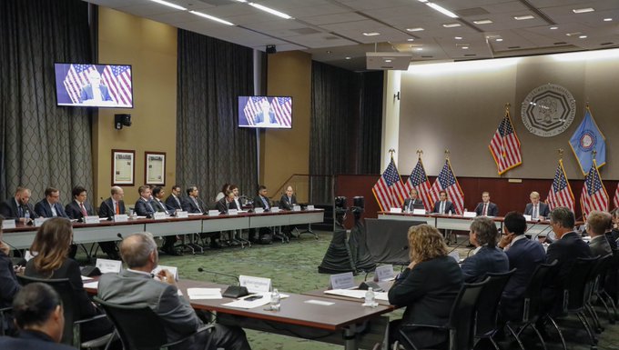 A formal CFTC (Commodity Futures Trading Commission) meeting is taking place in a conference room, with officials seated around a long table flanked by American flags and the CFTC seal on the wall, while participants face a panel from an audience of attendees. The scene reflects the CFTC's active leadership role in advancing U.S. digital commodities regulation, aligning with the post's message about the agency pushing forward with or without the Digital Asset Market Clarity Act (H.R. 3633).