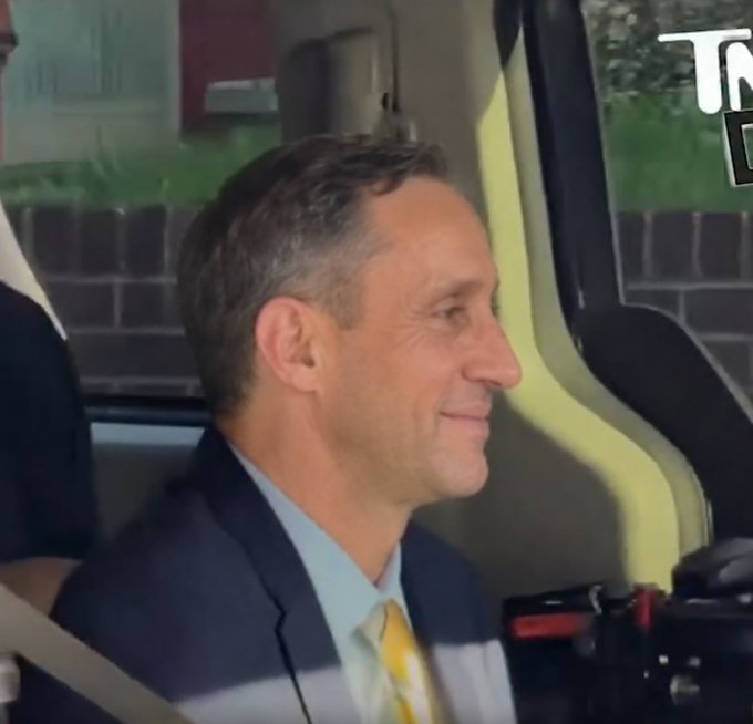 The image shows a smiling man in a dark suit with a yellow tie seated inside what appears to be a vehicle, likely waiting for the Clarity Act vote as referenced in the post. The "T" and "B" visible in the upper right corner suggest this is from a news broadcast, fitting the context of waiting on legislative news.