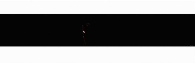 A mostly black image with white borders, showing a very faint dark silhouette or shape barely visible in the center.