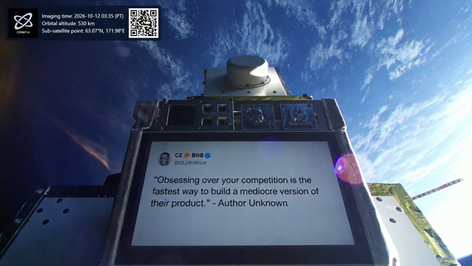 A satellite in orbit displaying a quote attributed to CZ @BNB (@cz_binance): 'Obsessing over your competition is the fastest way to build a mediocre version of their product.' - Author Unknown. Imaging time: 2026-10-12 03:35 (PT).