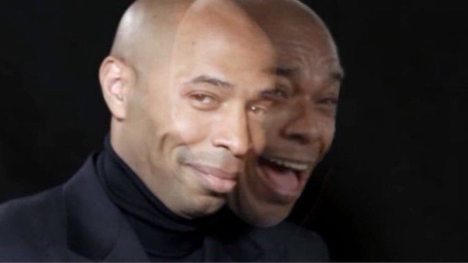 A close-up portrait of a smiling bald man wearing a black turtleneck against a dark background, with an overlapping double-exposure effect on his face.