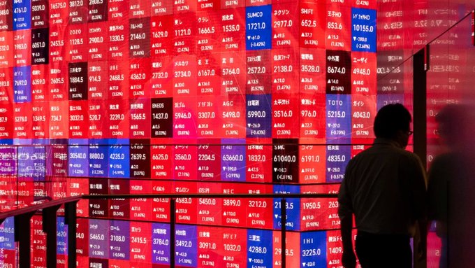 An investor stands before a large electronic board displaying a sea of red, showing sharp losses across Japanese stock tickers like SUMCO, TOTO, and TDK with double-digit percentage drops. The image visually echoes the post's frustration, capturing the painful stock market sell-off the author encountered after fleeing a stagnant crypto market.