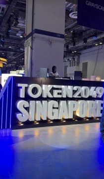 A convention display at TOKEN2049 SINGAPORE featuring illuminated signage on a stage area.