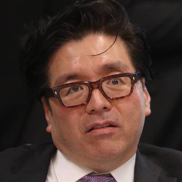 The image features a man wearing glasses and a suit with a purple tie, sitting and looking off to the side. There are also words like "BITMINE" and "ETH," which appear to be related to some form of digital currency or financial analysis concept. The main subject in the picture is the man's serious expression as he gazes into the distance.