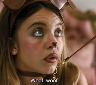 A young woman with dog ears and a painted nose has a thin stick in her mouth, with the subtitle 'Woof, woof.'