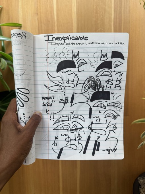A hand holds open a lined notebook displaying abstract black ink drawings and doodles, with the heading 'Inexplicable - Impossible to explain, understand, or account for' and 'AUGUST 2026'.