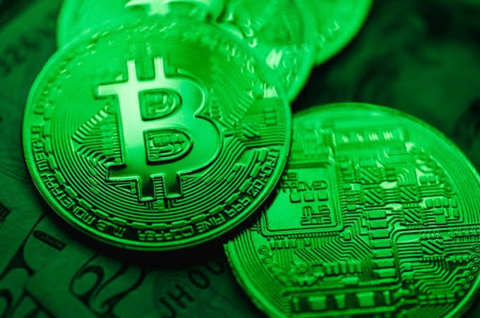 Two glowing green Bitcoin coins rest atop a stack of US currency, one displaying the iconic ₿ logo and the other revealing its intricate circuit-like reverse design, with visible inscriptions reading "BITCOIN DIGITAL COPPER" and "FINE COPPER." The image visually reinforces the breaking news announcement of BlackRock's massive $50.2 million Bitcoin purchase, using the vibrant green hue to evoke financial markets while symbolizing the growing institutional adoption of cryptocurrency.