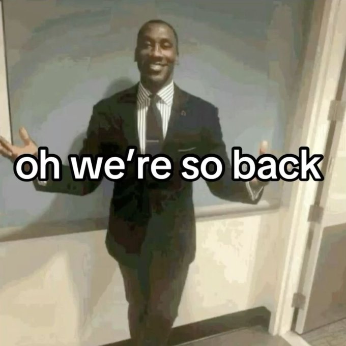 Meme image of a smiling man in a black suit with arms outstretched, overlaid with the text 'oh we're so back'.