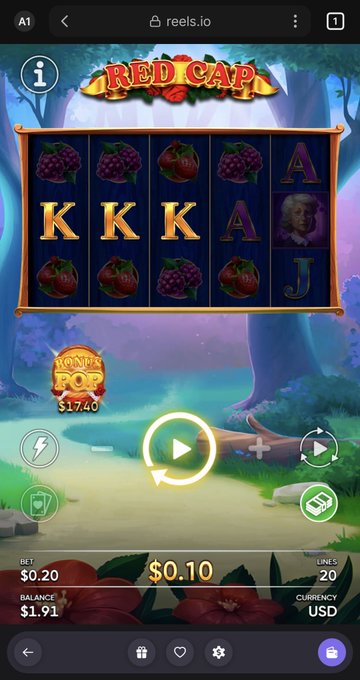 The image shows an advertisement for a slot machine game, with a large screen displaying the game's interface. The main focus of the image is a slot machine that has a "Red Cap" theme, featuring various fruits such as grapes, strawberries, and apples. The slot machine also includes a "KK KJ A" slot, which could be related to the game's scoring system or other gameplay elements. The background of the image features a forest setting with trees and bushes, adding to the overall atmosphere of the advertisement.