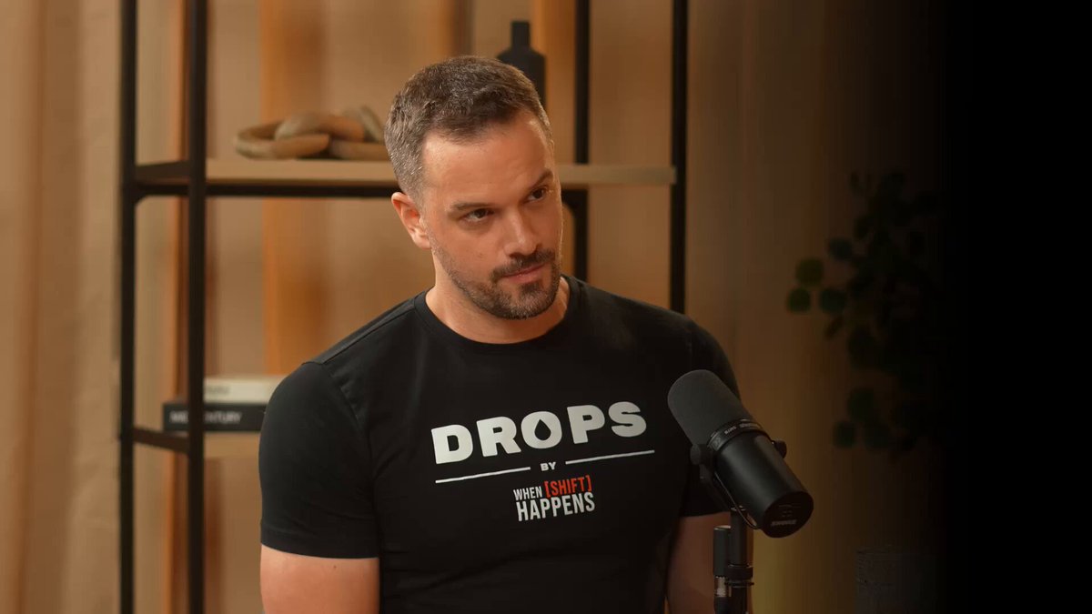 The image features a man wearing a black t-shirt with white text that says "DROPS E36" and "from NFTs to Nasdaq @ 26 - and now building the future of commodities @henry mcphie". The man is standing in front of a microphone, suggesting he might be hosting or participating in an interview. There are also books visible in the background, which could potentially be related to the content of the post.