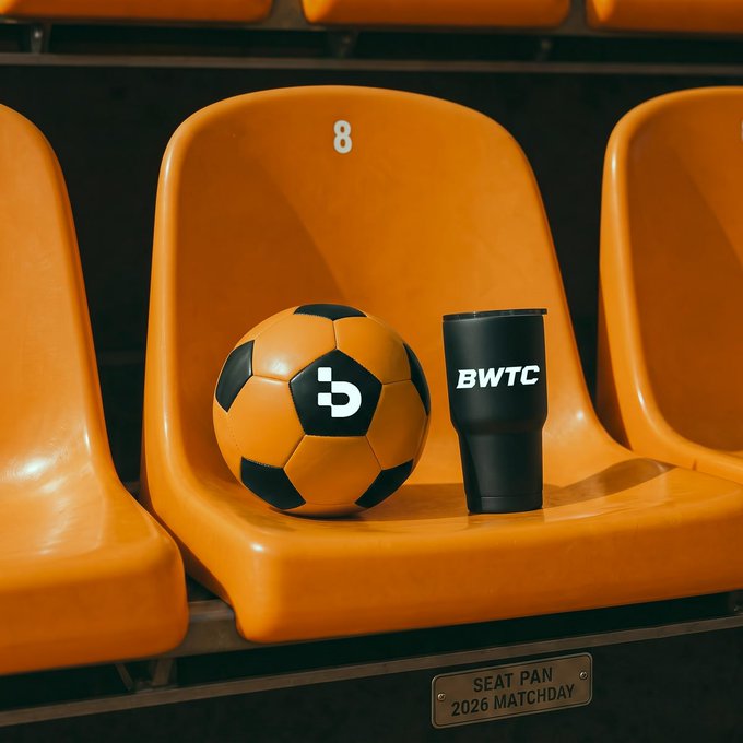 An orange soccer ball with a "D" logo sits beside a black "BWTC" tumbler on stadium seat #8, perfectly capturing the "front-row view" vibe of matchday readiness. The "SEAT PAN - 2026 MATCHDAY" plate below ties it all together with a nod to the upcoming season.