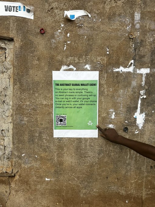 A person's hand is shown posting or holding up a green flyer on a weathered concrete wall, with the flyer promoting "The Abstract Global Wallet (AGW)" and instructions to scan a QR code or use a web3 wallet, alongside a "VOTE" sticker visible in the upper left corner. The image reflects the poster's emotional investment in the Abstract ecosystem, as the flyer represents their tangible contributions like banners and content creation aimed at supporting the community.