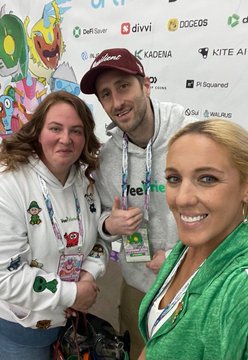Three people posing for a photo at what appears to be a crypto/Web3 event, with sponsor logos like Drift, KADENA, and KITE AI visible in the background; the middle person is wearing a tee.one hoodie.