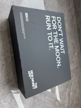 A black HOKA shoe box with white text reading 'DON'T WAIT FOR THE MOON, RUN TO IT' on the lid.