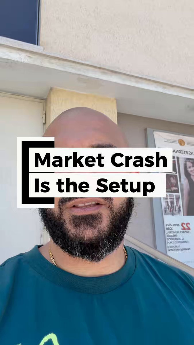 The image features a bald man with a beard wearing a blue shirt, standing against a wall with a poster behind him that says "Market Crash Is The Setup".