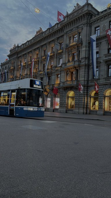 A tram labeled "16 Mitherrli" passes by a grand building adorned with Swiss flags. The image visually reinforces the post's mention of being on vacation in Switzerland.