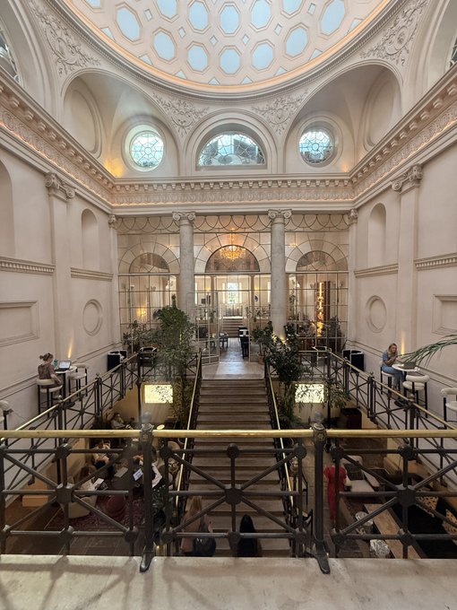 A grand interior view of a domed hall with a central staircase, ornate railings, and dining tables below, suggesting an upscale restaurant or event space. The elegant architecture with its patterned skylight and classical columns aligns with the post's praise of a beautiful day at House of Sol.