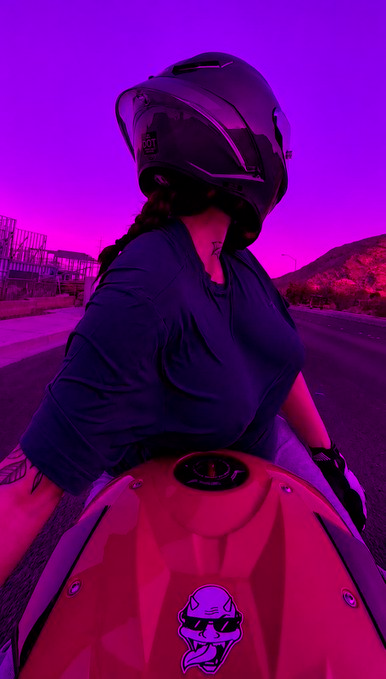 A motorcyclist wearing a helmet and dark clothing poses next to a red motorcycle, with the entire scene bathed in a striking purple and pink neon glow, complementing the "RED" theme and bullish "0.60 incoming" sentiment of the post.