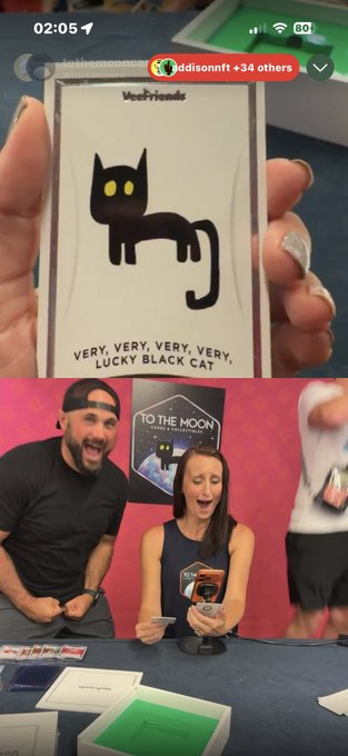 A split image showing a hand holding a 'Very, Very, Very, Very Lucky Black Cat' sticker (top) and two people reacting excitedly while opening trading cards in what appears to be a live stream recording (bottom).