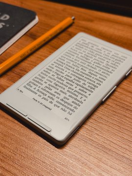 An Xteink e-reader displays a page of text in Spanish on a wooden desk beside a yellow pencil, showcasing the compact e-ink device being promoted in the post. The caption could read: "An Xteink e-reader displays Spanish text next to a pencil, showcasing the minimalist reading experience that makes this little device worth buying."