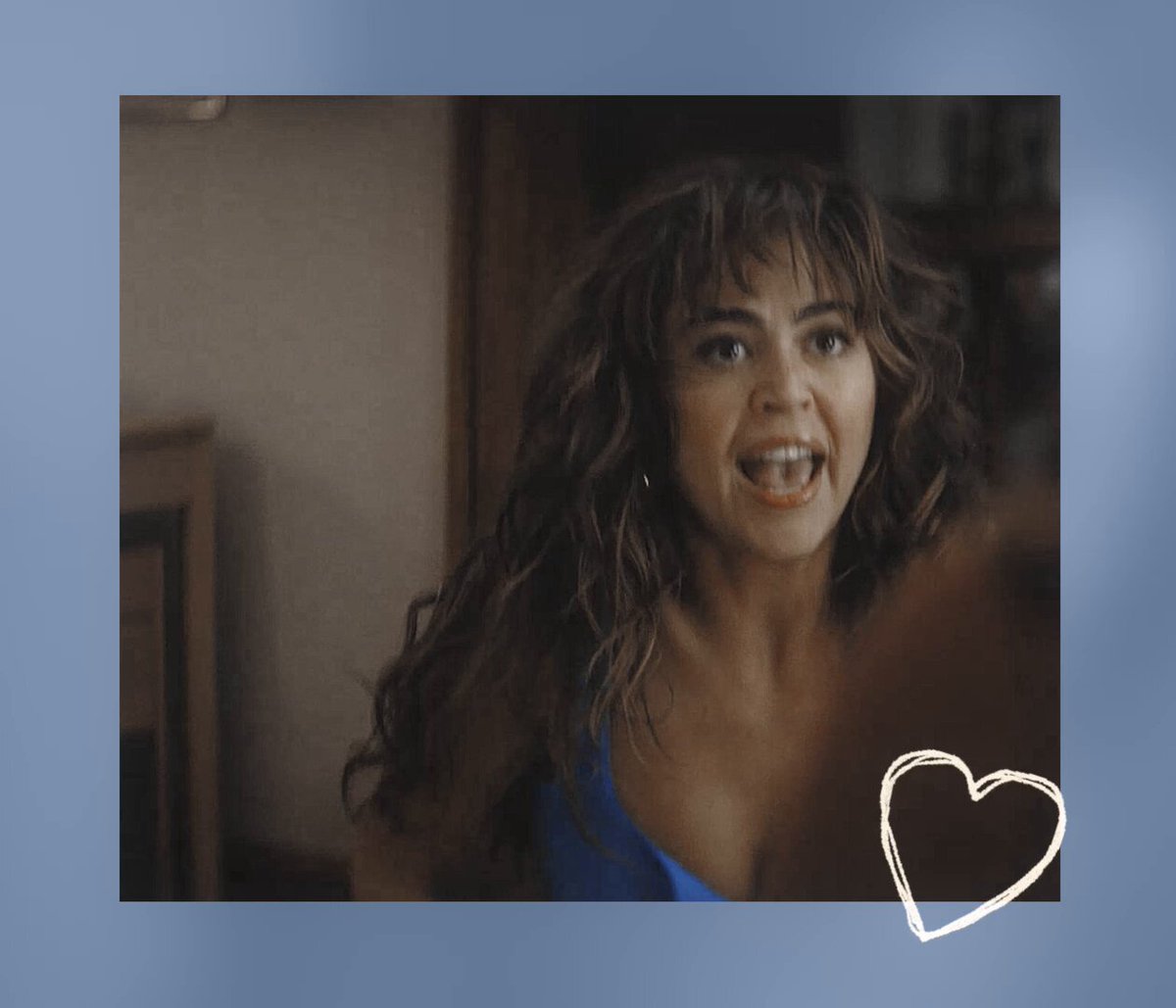 The image features a woman with long brown hair wearing a blue dress, who appears to be smiling at the camera. She has her mouth open wide as if she's making a funny face or saying something amusing. The caption "BROOKEALLIE TETHER IS REAL AND STRONG" is written below the photo, which seems to be related to the image of the woman in blue dress and her facial expression.
