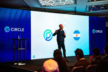 Jeremy Allaire, CEO of Circle, stands on stage presenting the Circle logo alongside the Argentine flag, reflecting the post's message of growing momentum for Circle, Arc, and USDC in Argentina's crypto ecosystem.
