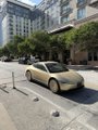 A gold/champagne-colored Tesla Cybercab is driving on a street in downtown Austin, with tall office buildings and trees lining the road. The image visually supports the post's claim about Cybercabs becoming a common sight in the city.