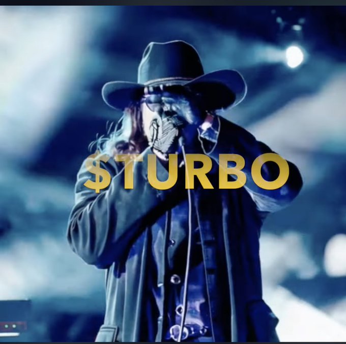 A stylized image of a singer in a black hat and coat performing on stage with the text '$TURBO' overlaid in gold.