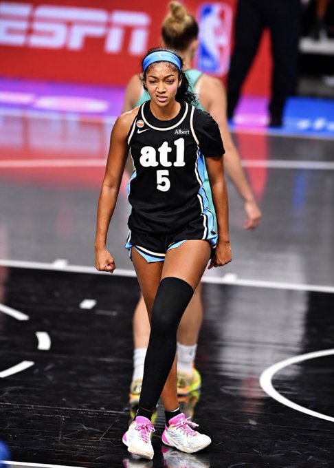 An Atlanta Dream WNBA player wearing a black 'atl 5' jersey with teal trim and a black leg sleeve, walking on the court during a game.