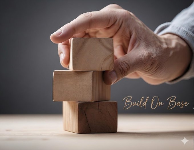 A hand carefully placing a wooden block on a stack, with the cursive text 'Build On Base' in the corner.