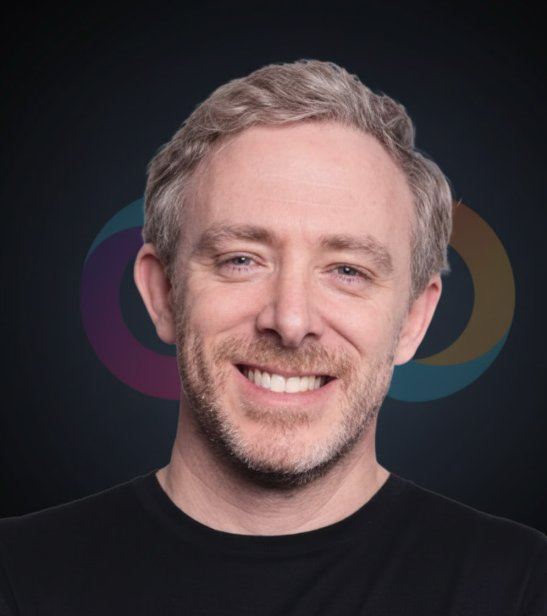 A headshot of a smiling man with gray hair and a black shirt against a dark background featuring a multicolored infinity symbol logo.