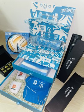 The image shows an opened gift box containing official World Cup merchandise, including a blue cap and what appears to be a wrapped item, all packaged in a decorative blue box featuring World Cup-themed graphics. The accompanying post highlights the excitement of receiving this merchandise from @deepcoin_cn, with the user expressing enthusiasm for the craftsmanship and their support for Argentina.