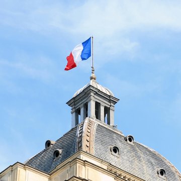 The French flag flies atop a domed building, likely a government or civic structure in France. The image relates to the post by visually establishing the French setting of the story about the couple whose home was repeatedly targeted after criminals discovered the previous crypto-millionaire owners' address online.
