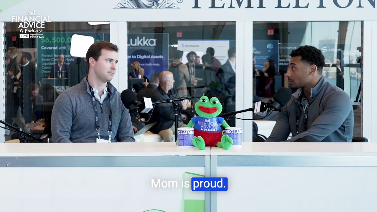 Two men record an episode of the "Not Financial Advice" podcast at the Blockworks Digital Asset Summit 2026, with their green frog mascot sitting between them on a desk beside two #CLAIMB #DISCLAIM cups, while the caption "Mom is proud." appears below—capturing a candid moment from the TradFi/Crypto crossover discussion.