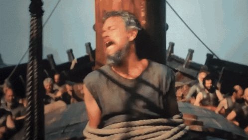A scene from a film shows a bearded man in tattered clothing tied to a ship's mast, appearing to shout.