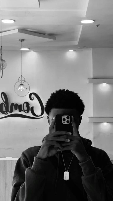 A person in a hoodie takes a black-and-white mirror selfie, holding a phone in front of their face, with a "Cool" neon sign visible in the background. The image conveys a reflective, community-focused "gm" vibe matching the post's motivational crypto message, while the mirrored "Cool" text plays on the introspective theme of staying focused and winning together this new week.