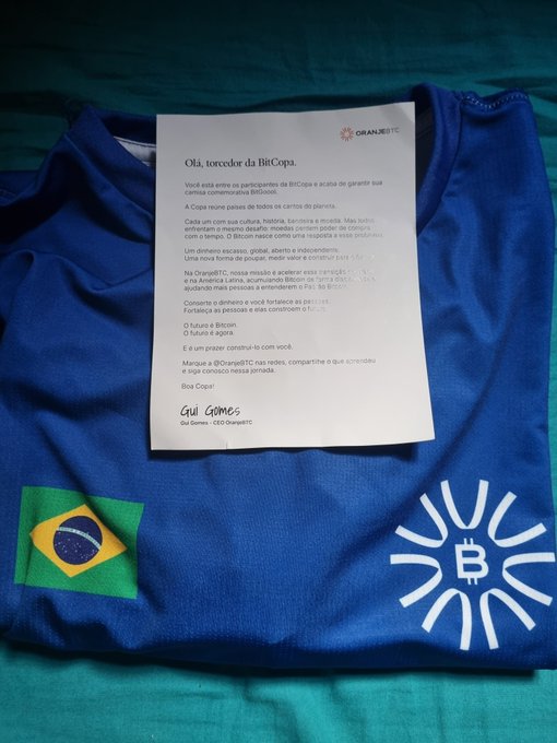 A blue Bitcoin jersey featuring the Brazilian flag and the Bitcoin logo is laid out with a letter from "Gul Gomes, Gol Gomes - CEO OranjeBTC" welcoming recipients to "BitCopa" and inviting them to join the BitGols community, reflecting the post's message about the growing "OranjeBTC" fanbase.