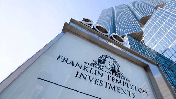 An exterior sign for "FRANKLIN TEMPLETON INVESTMENTS" featuring the Benjamin Franklin portrait logo stands in front of a modern glass skyscraper with the letters "ZOO" partially visible above.