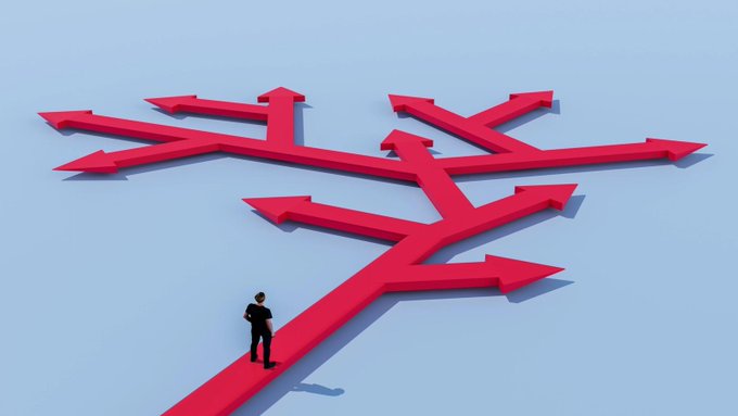 A conceptual 3D illustration shows a man standing at the base of multiple large red arrows pointing in different directions, symbolizing difficult decisions.