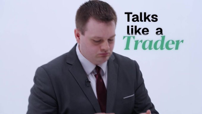 A man in a grey suit and dark tie looking down, accompanied by the words 'Talks like a Trader' in black and green text.