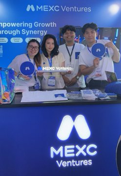 Three people pose at a MEXC Ventures booth holding branded signs, with the text 'MEXC Ventures' and 'Empowering Growth through Synergy' visible in the background.